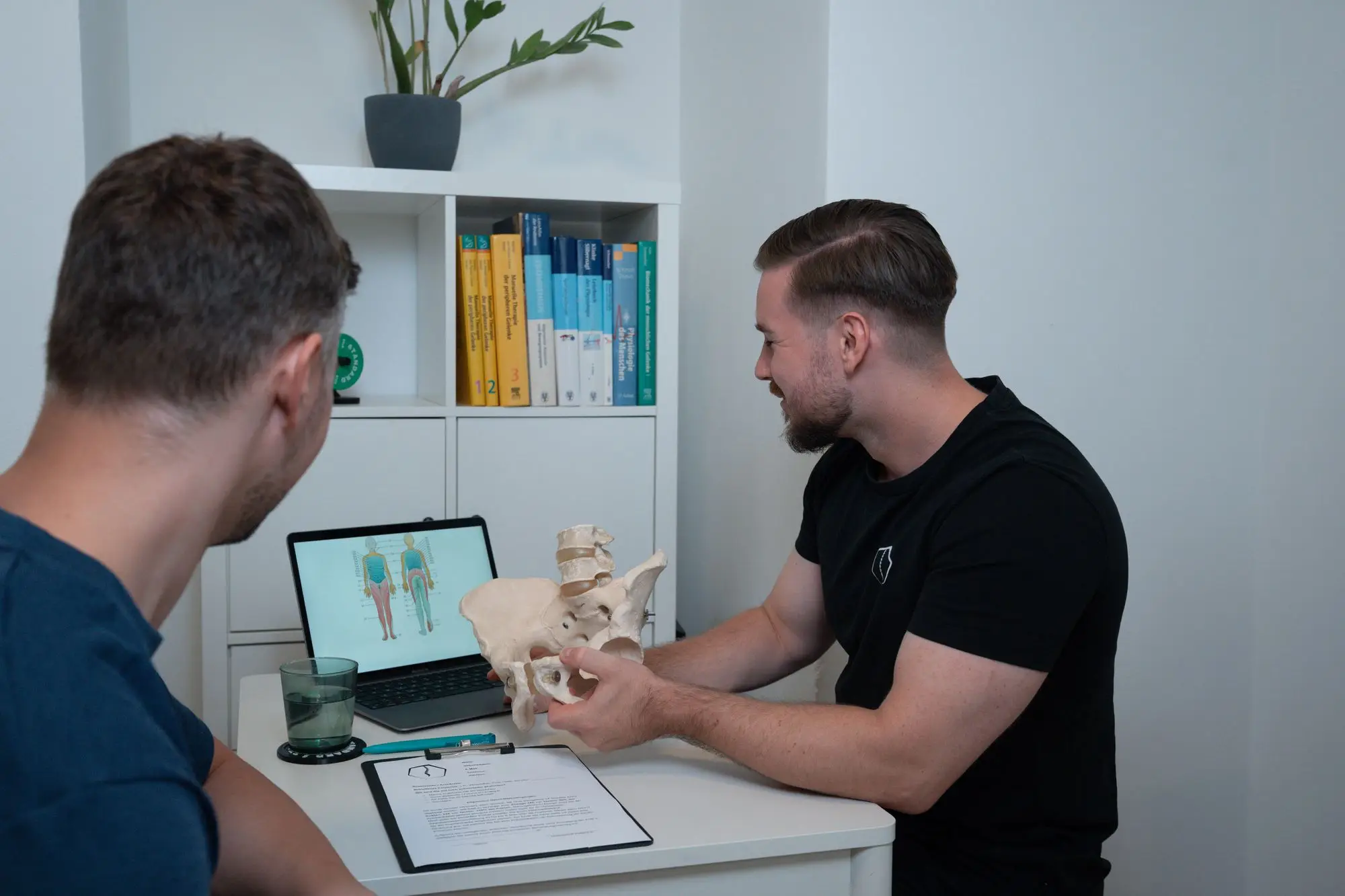 Florian Bader erklärt einem Patienten das Becken am anatomischen Modell